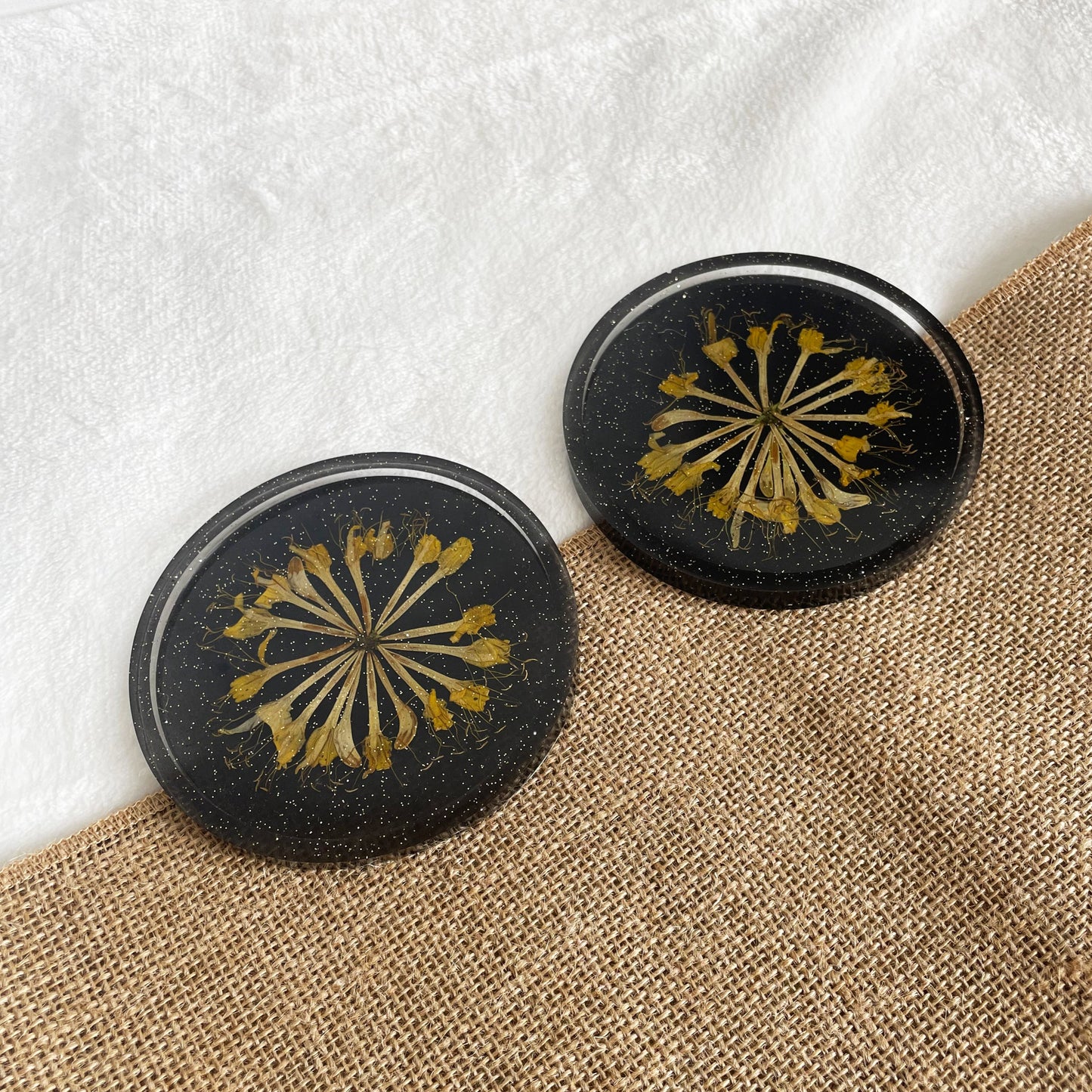 Handmade round resin coaster, black base with yellow flower accent, artisan home accessory