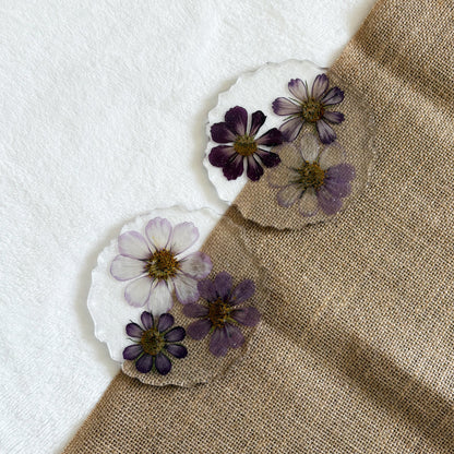 Clear resin coaster with embedded purple flowers, nature-inspired handmade décor piece