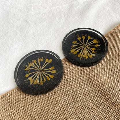 Handmade round resin coaster, black base with yellow flower accent, artisan home accessory