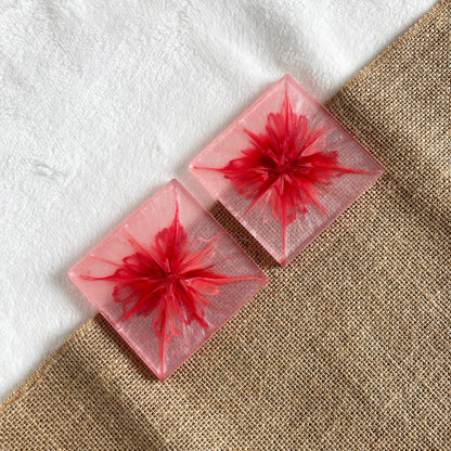 Square handmade resin drink coaster with pink and white marble effect shown on wooden table